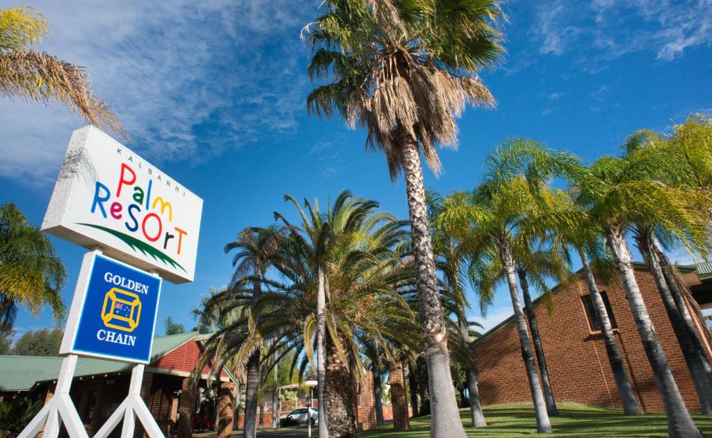 Entrance sign and palm trees at Kalbarri Palm Resort on a sunny day.