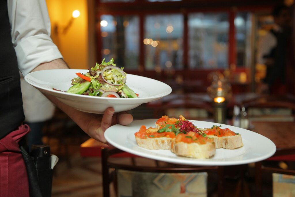 A waiter serving fresh bruschetta and a garden salad in a cozy Kalbarri restaurant.
