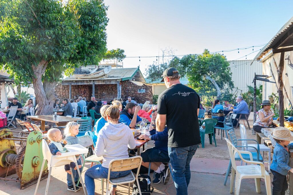 Finlay's Kalbarri outdoor dining area with guests enjoying a relaxed meal under the trees.