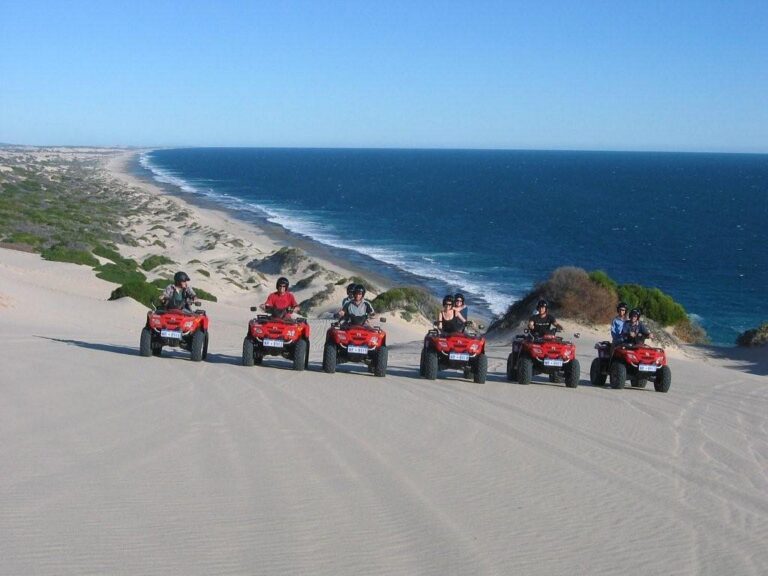 A group of quadbike riders lined up on a sand dune with sweeping views of Wagoe Beach and the deep blue Indian Ocean in Kalbarri, Western Australia.