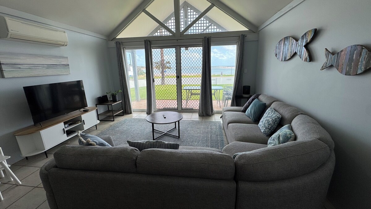 A row of cozy beachside cabins in a coastal caravan park, surrounded by native vegetation with a warm sunset glow. Perfect for budget-friendly travellers and road-trippers looking for accommodation in Kalbarri.