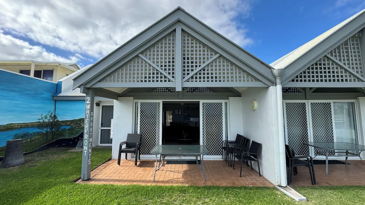 Self-contained holiday cabin at a caravan park in Kalbarri, Western Australia, with outdoor seating and palm trees in the background.