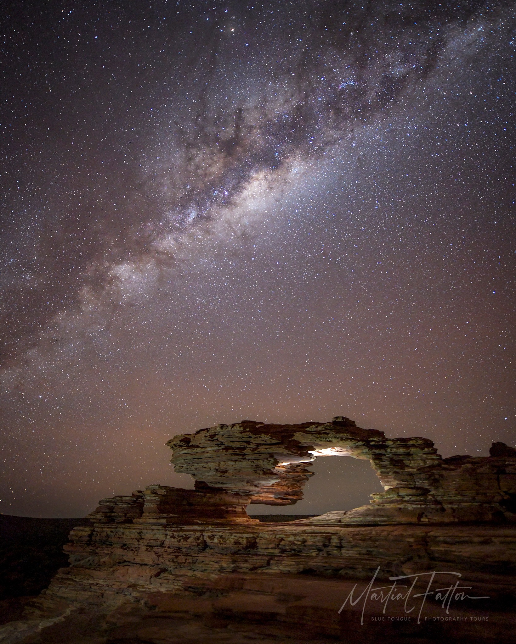 Stargazing in Kalbarri. The Milky Way galaxy above Nature’s Window rock formation in Kalbarri National Park, Western Australia