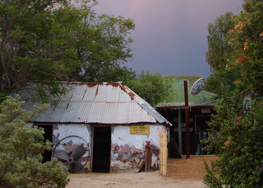 The historic Von Bibra Cottage at Murchison House Station, a rustic stone and corrugated iron building with a satellite dish and old station equipment.